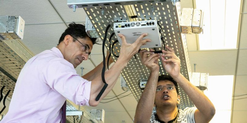 Aloizio DaSilva and Vikas Krishnan install a component of the testbed 
